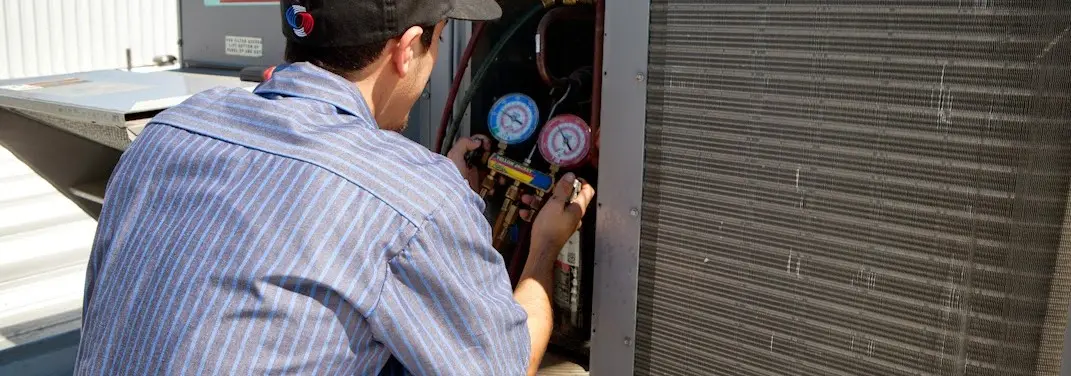 HVAC technician servicing a condenser unit in Maxatawny